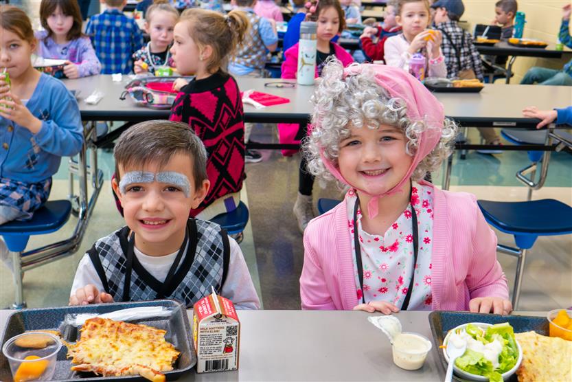 girl and boy in cafeteria in 100 year old outfits